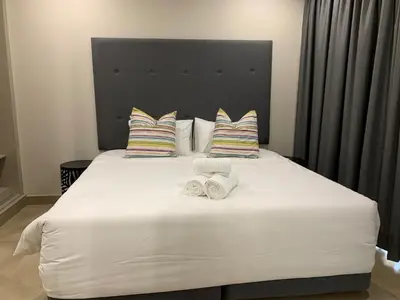 a bedroom with a large white bed with two towels at 77 On Burger in Polokwane