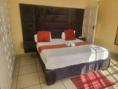a bedroom with a large bed with orange and white pillows at Hadassa Lodge in Burgersfort