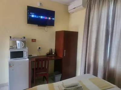 a room with a kitchen with a refrigerator and a tv on the wall at Hadassa Lodge in Burgersfort