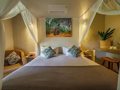 a bedroom with a bed and a painting on the wall at Umbhaba Eco Lodge in Hazyview