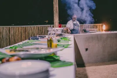 a man standing behind a table with plates of food at Umbhaba Eco Lodge in Hazyview