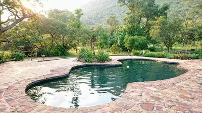 a pool of water in a yard with trees at Cross Pollination Chalets & Camping in Vaalwater