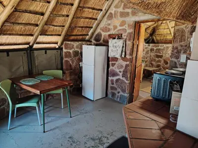 a kitchen with a table and a refrigerator at Cross Pollination Chalets & Camping in Vaalwater