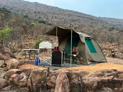 a tent with a table and chairs on a hill at Cross Pollination Chalets & Camping in Vaalwater