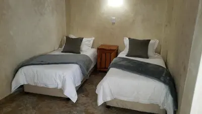 a room with two beds and a night stand withskirts at Berchtesgaden Game Ranch & Lifestyle Farm in Vaalwater