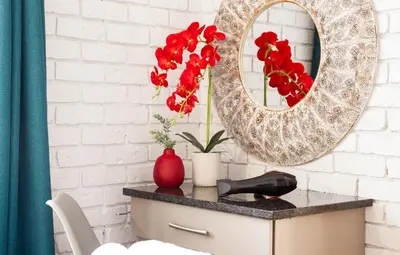 a table with a mirror and red flowers on it at Rozelee Rest 1 in Nelspruit