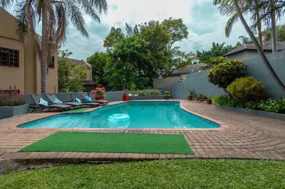 a swimming pool in a yard with chairs and trees at Rozelee Rest 1 in Nelspruit