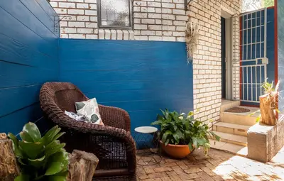 a wicker chair sitting on a patio next to a blue wall at Rozelee Rest in Nelspruit