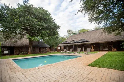 a swimming pool in front of a house at Kilima Private Game Reserve & Spa in Gravelotte