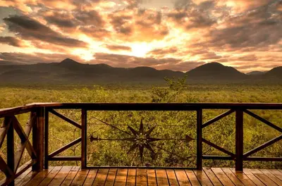 a sunset over a field with mountains in the background at Kilima Private Game Reserve & Spa in Gravelotte
