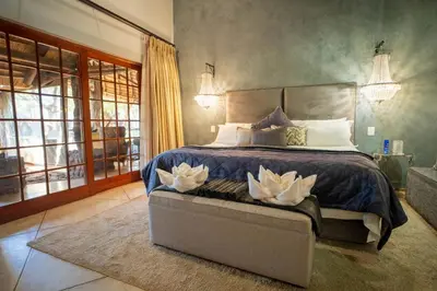 a bedroom with a bed with two white flowers on it at Kilima Private Game Reserve & Spa in Gravelotte