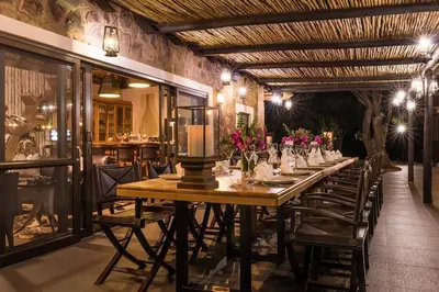 a long table in a restaurant with flowers on it at Buccara Waterberg - Molapo in Lephalale