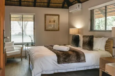 a bedroom with a large white bed and a chair at Buccara Waterberg - Molapo in Lephalale