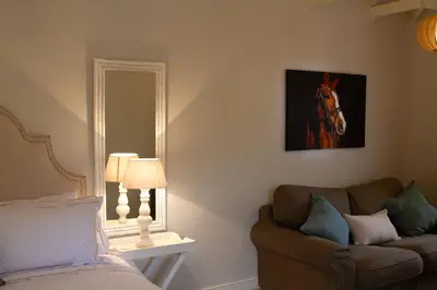 a bedroom with a couch and a horse picture on the wall at The Stables, Beaulieu Kyalami in Midrand