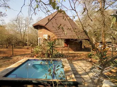 a brick house with a swimming pool in front of it at Chip n Debs Kruger Vacations in Marloth Park