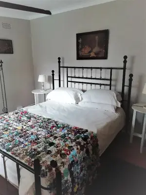 a bedroom with a bed with a floral blanket on it at Fountain Baths Guest Cottages in Barberton