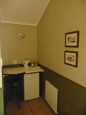 a small kitchen with a counter and a table at Fountain Baths Guest Cottages in Barberton