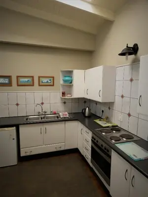 a kitchen with white cabinets and a sink at Fountain Baths Guest Cottages in Barberton