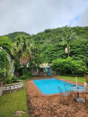 a swimming pool in the yard of a house at Fountain Baths Guest Cottages in Barberton