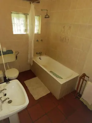 a bathroom with a tub and a toilet and a sink at Fountain Baths Guest Cottages in Barberton
