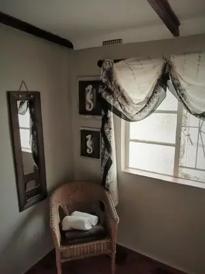 a room with a chair and a window and a mirror at Fountain Baths Guest Cottages in Barberton