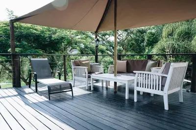 a deck with chairs and a table and an umbrella at Rockview Lodge in Nelspruit