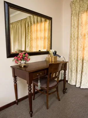 a desk with a mirror and a lamp and flowers on it at Stans &co in Bethal