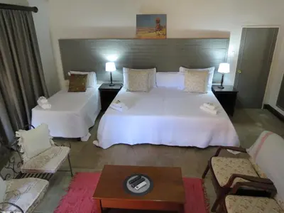 a hotel room with two beds and a couch at Olden Rose Place in Lephalale