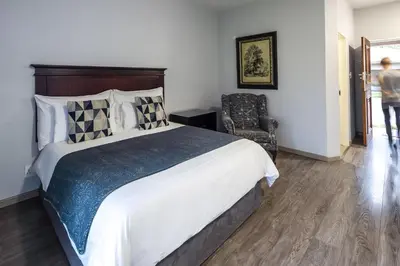 a bedroom with a large bed and a chair at Olden Rose Place in Lephalale