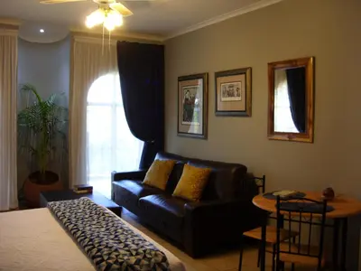 a living room with a black leather couch and a table at Little Umhlanga. Sunflower suite. in Pretoria