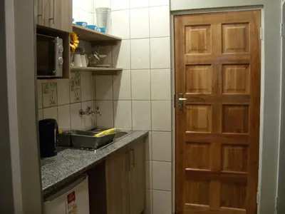 a small kitchen with a sink and a door at Little Umhlanga. Sunflower suite. in Pretoria