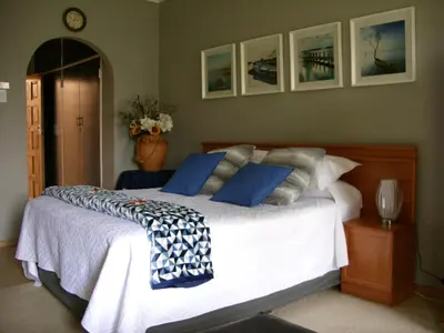 a bedroom with a large white bed with blue pillows at Little Umhlanga. Sunflower suite. in Pretoria