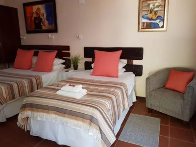 a hotel room with two beds and a chair at Ngwenya Boutique Hotel in Lephalale