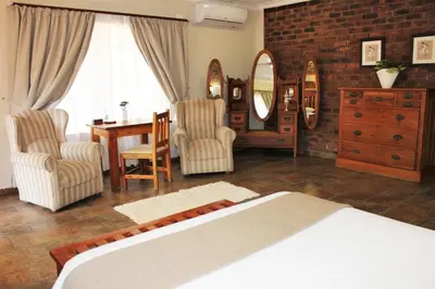 a bedroom with a bed and a table and chairs at Ngwenya Boutique Hotel in Lephalale