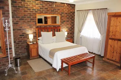 a bedroom with a bed and a brick wall at Ngwenya Boutique Hotel in Lephalale