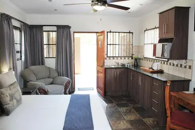 a kitchen with wooden cabinets and a ceiling fan at Ngwenya Boutique Hotel in Lephalale