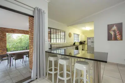a kitchen and dining room with a counter and stools at Shades of Nature in Marloth Park