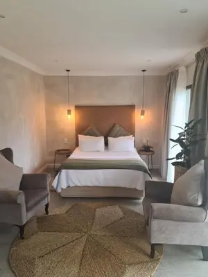 a bedroom with a large bed and two chairs at Annie’s Place Self Catering 2 in Kempton Park