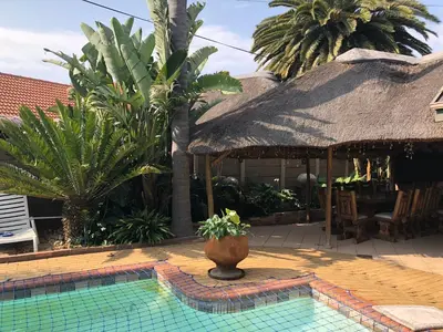 a house with a pool with a thatch roof at Annie’s Place Self Catering 2 in Kempton Park