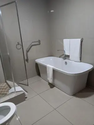a bathroom with a tub and a shower and a toilet at Khayalami Hotel - Emalahleni in Witbank