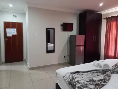 a hotel room with a bed and a refrigerator at Khayalami Hotel - Emalahleni in Witbank