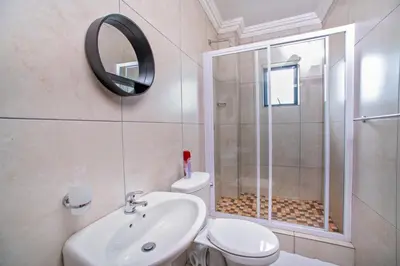 a bathroom with a shower and a toilet and a sink at Khayalami Hotel - Emalahleni in Witbank