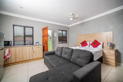 a bedroom with a couch and a bed with red pillows at Khayalami Hotel - Emalahleni in Witbank