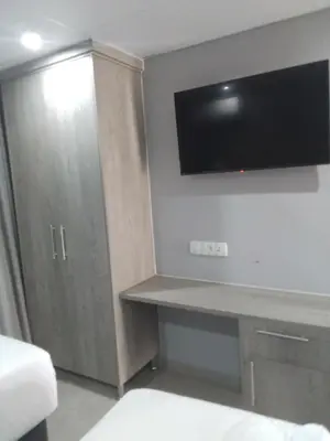 a room with a desk and a tv on the wall at Khayalami Hotel - Emalahleni in Witbank