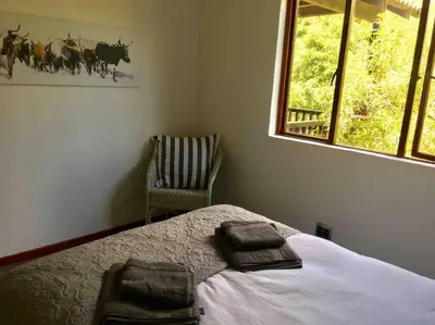 a bedroom with a bed and a chair and a window at Greenway Woods Chalet in White River