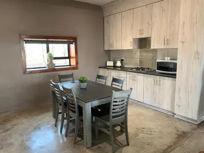 a kitchen with a table and chairs in a kitchen at Merino Stal Guest Farm in Ermelo