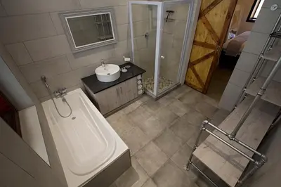 a bathroom with a tub and a sink and a shower at Merino Stal Guest Farm in Ermelo