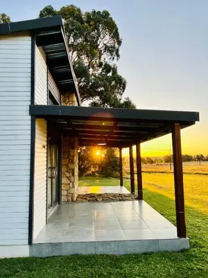 a house with a patio with the sunset in the background at Merino Stal Guest Farm in Ermelo