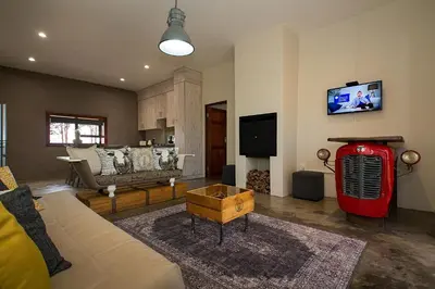 a living room with a couch and a tv at Merino Stal Guest Farm in Ermelo