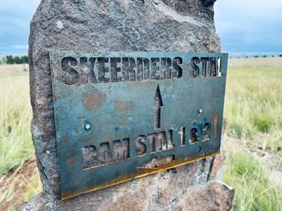 a metal sign on a rock in a field at Merino Stal Guest Farm in Ermelo